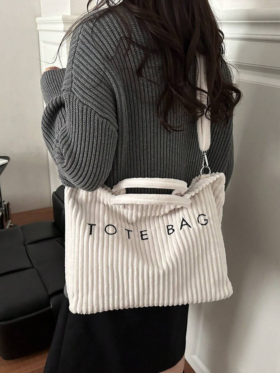 The New Retro-Chic Corduroy Hand Tote Bag Features A Hook And Loop Closure, Boasts A Lightweight And Minimalist Design, And Is Adorned With Letter Detailing. It Comes With An Adjustable Long Shoulder